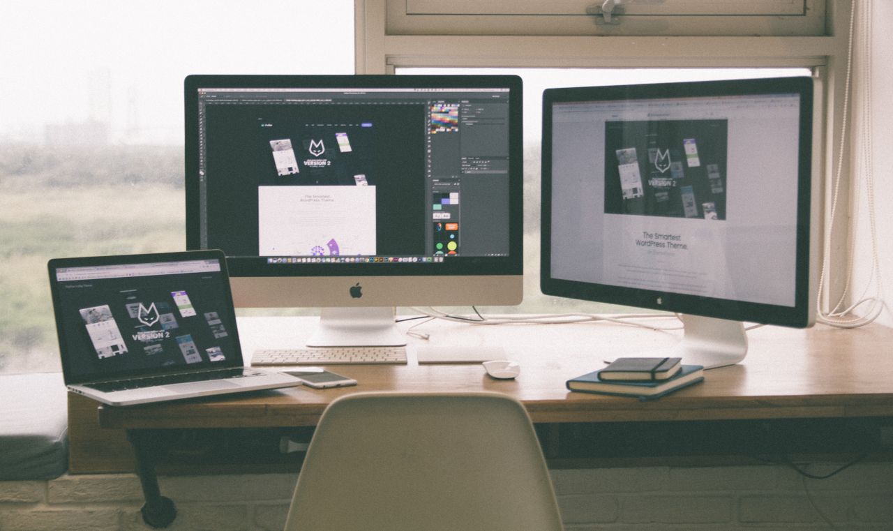 services-01 Stylish and efficient workspace with multiple monitors, laptop, and smartphone, showcasing a web design project.